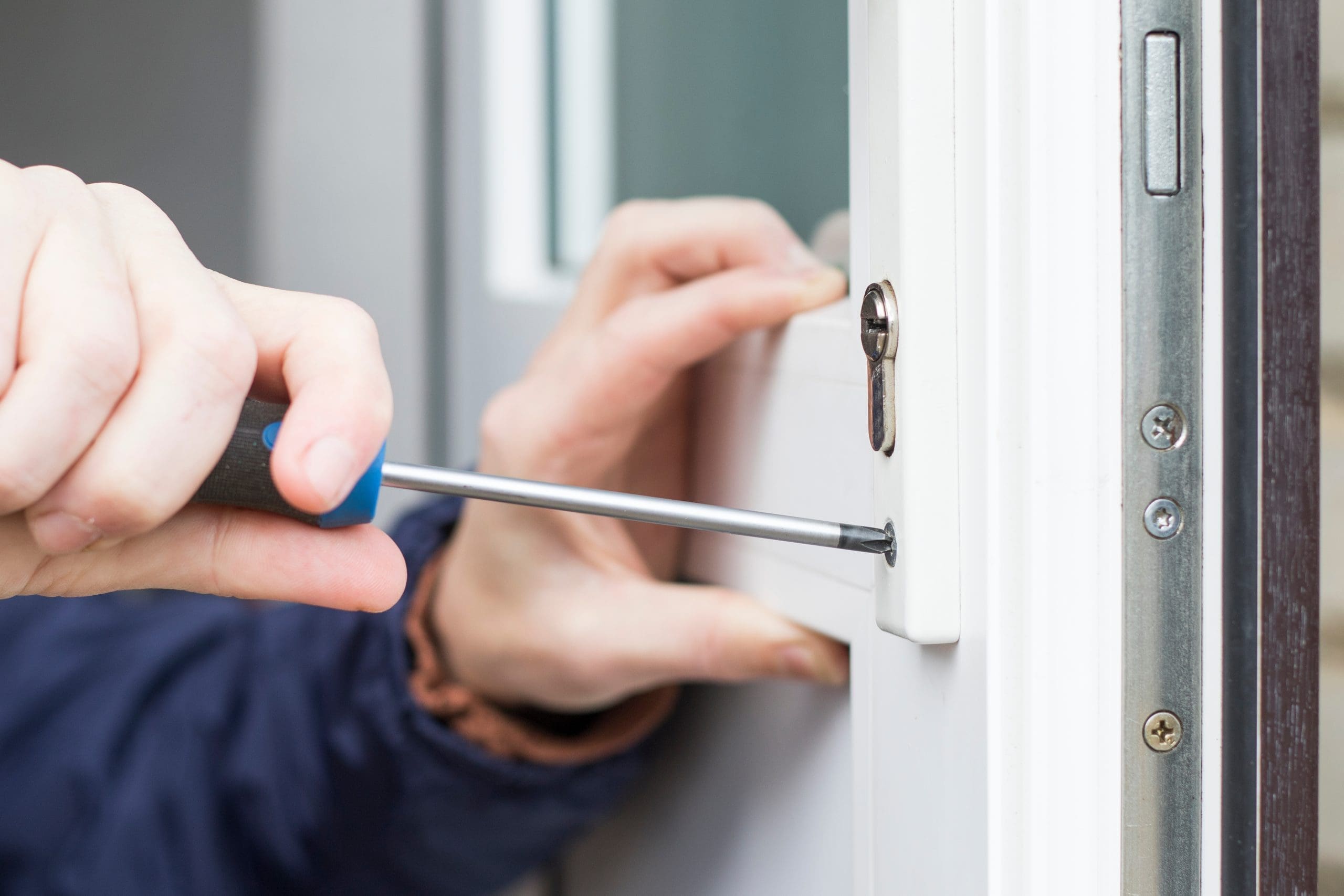 A technician using a screwdriver to repair and replace a UPVC door lock