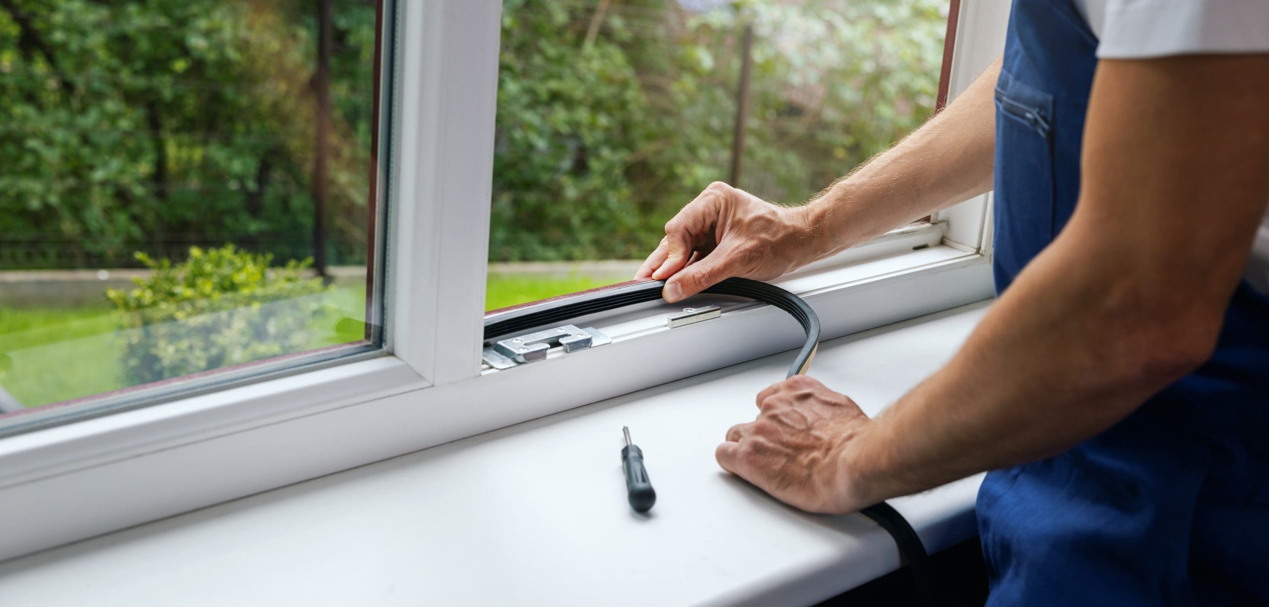 Technician fitting a new rubber gasket into a UPVC window frame